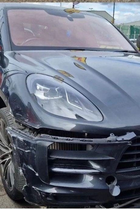 Black Porsche Macan with the front bumper and wing torn open after a collision